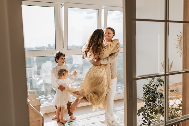 Parents dancing and playing around while their kids are watching them and smiling