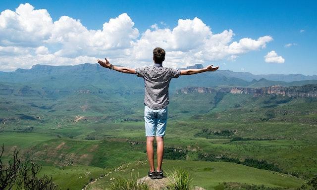 Guy at the top of hike holding his arms out