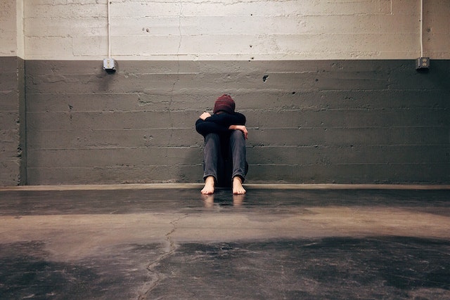 Person sitting folded and looking upset