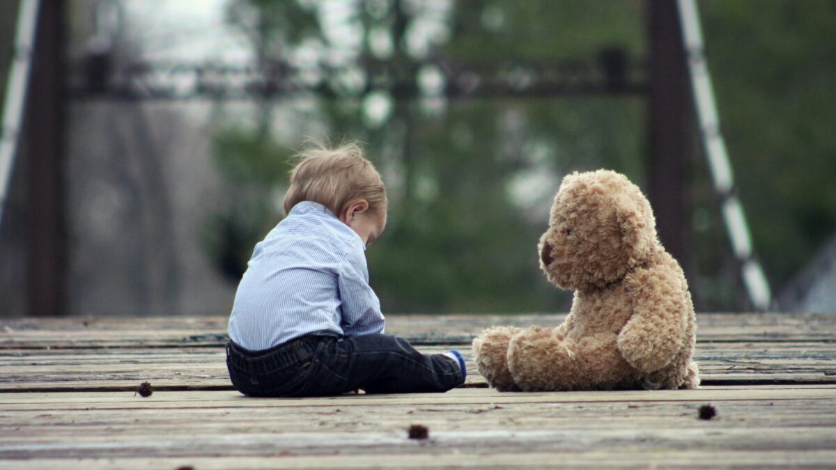 little boy sitting alone with teddy bear