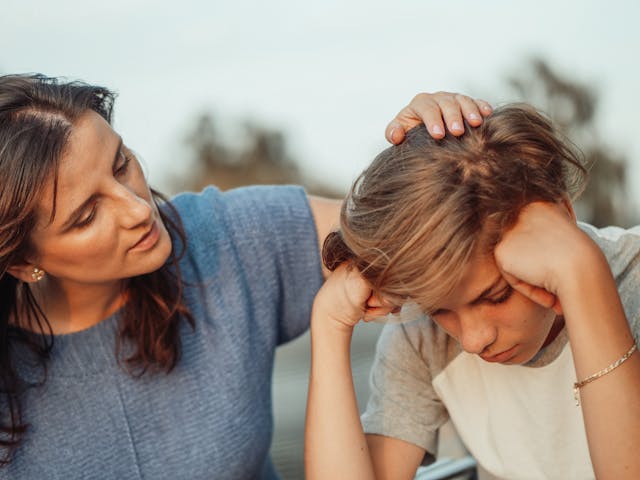 A woman comforting a stressed boy
